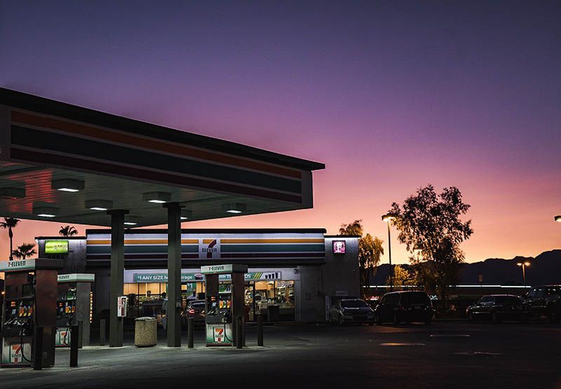 An empty petrol station with a small shop during sunset.