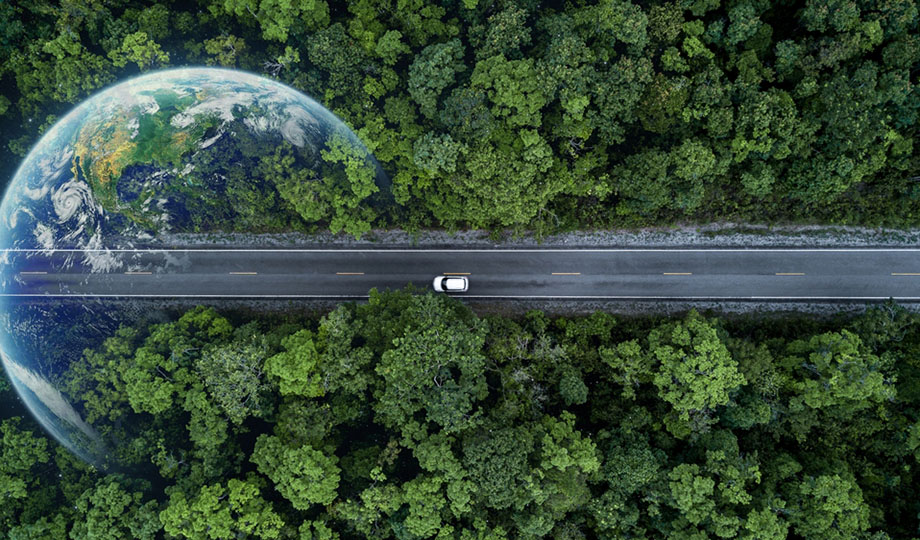 An EV car is running on the street in the forest.