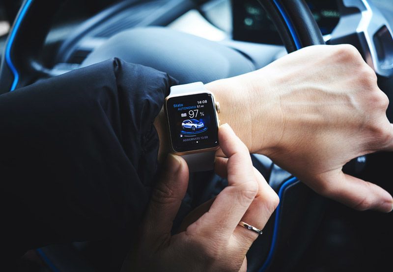 A married EV driver that checks the status of her car's battery on her smartwatch. The watch shows the battery is 97% full.