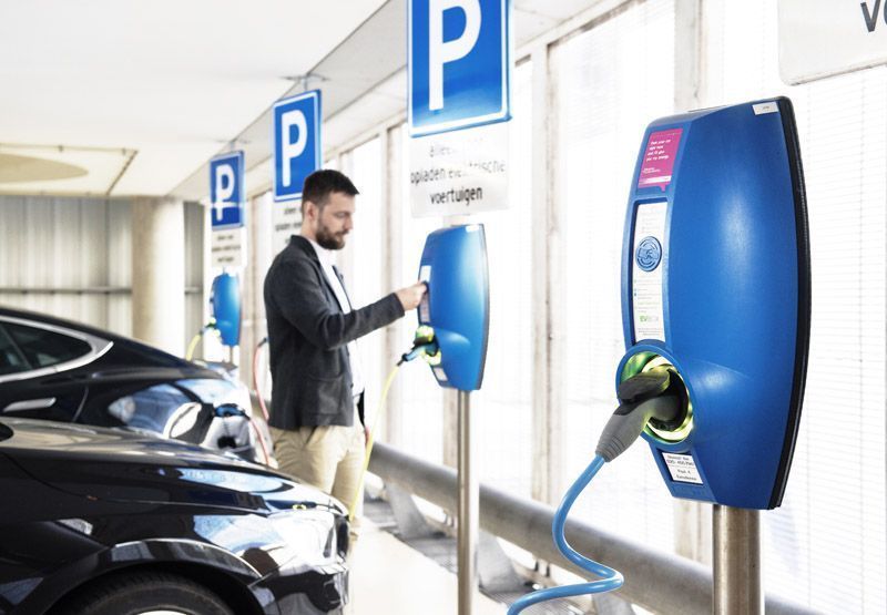 man laadt elektrische auto Tesla op in parkeergarage met EVBox BusinessLine laadpaal