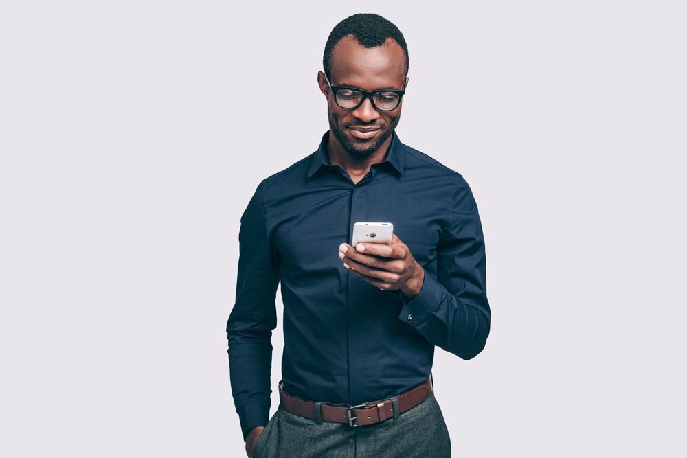 A man looking at his smart phone and smiling.