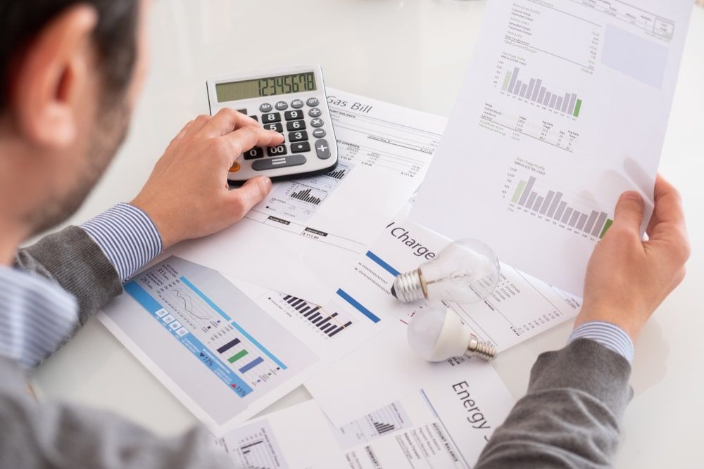 Person looking at bills with calculator in hand.