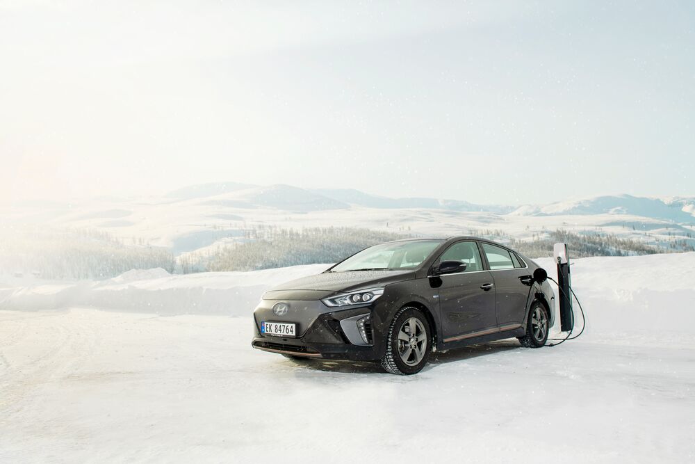 Car being charged in EVBox Elvi charging station in the snow.