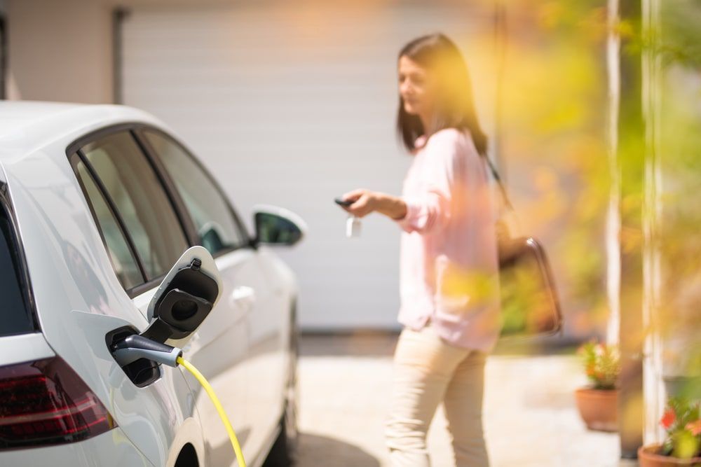 Woman charging white electric car.