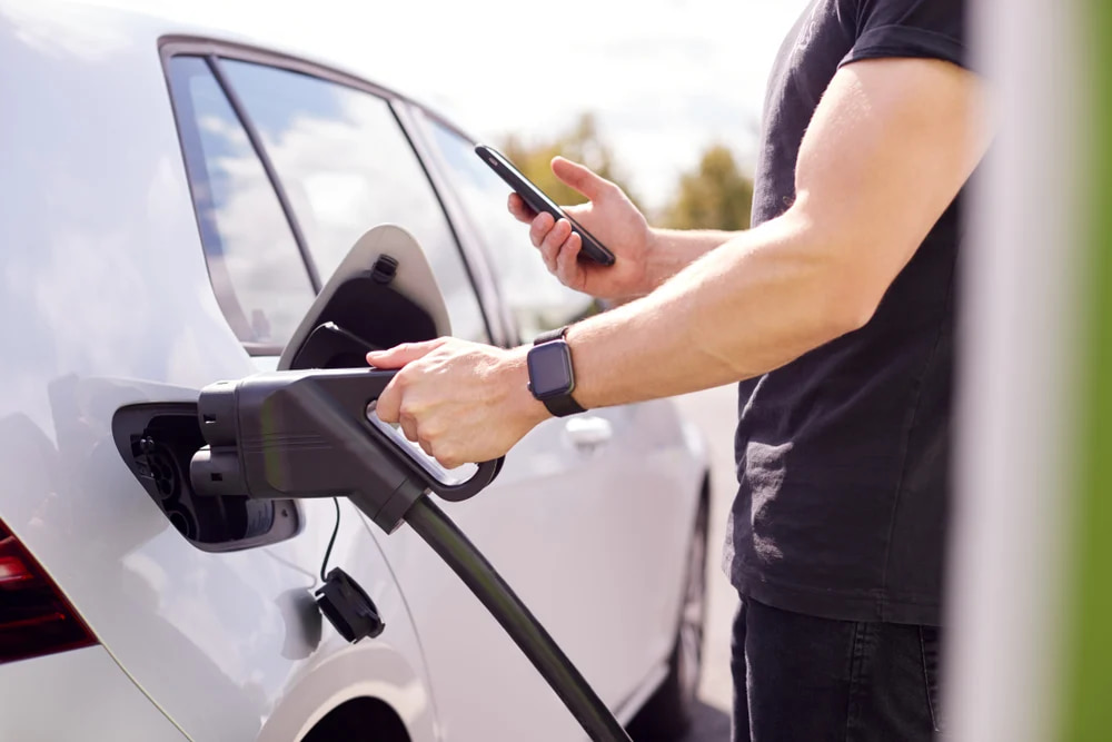 A man using a DC fast charging station to charge his car more quickly.