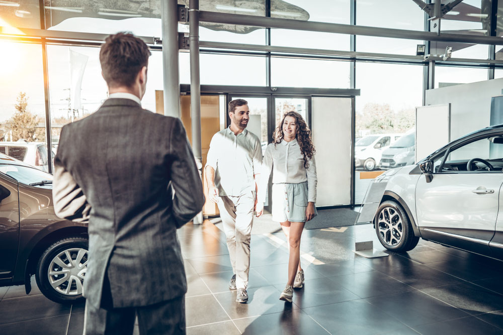 A couple are walking beside an EV car.