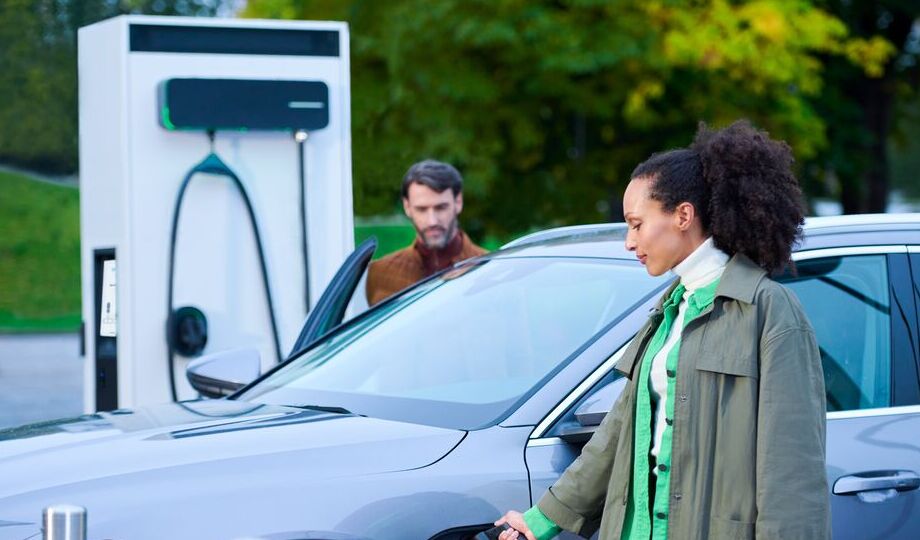 A man and a woman are charging their EV using EVBox Troniq Modular DC fast charging station.