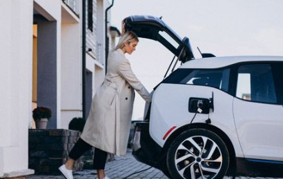 Woman loading boot of electric car while it charges