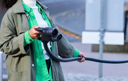 A woman is using DC fast charging station to charge her car.