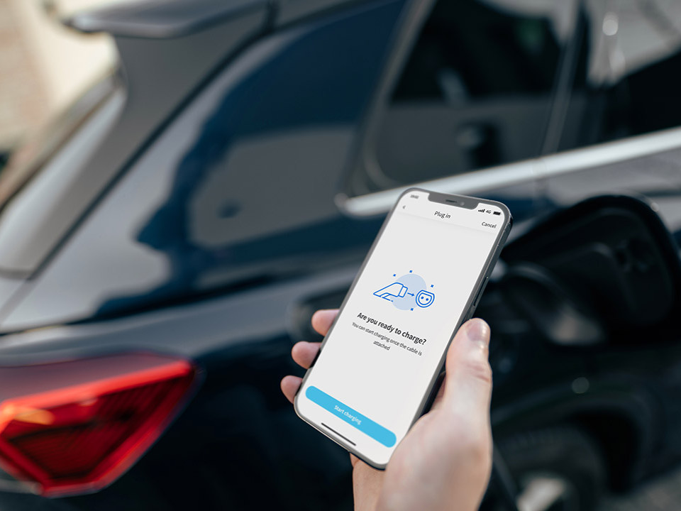 A person holding a smartphone next to a car