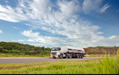 A heavy distribution truck driving on a country road on a sunny day.